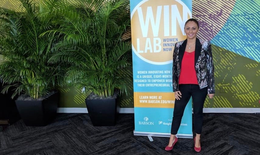 Liz Pasillas junto a un banner de WIN Lab Women Innovating Now